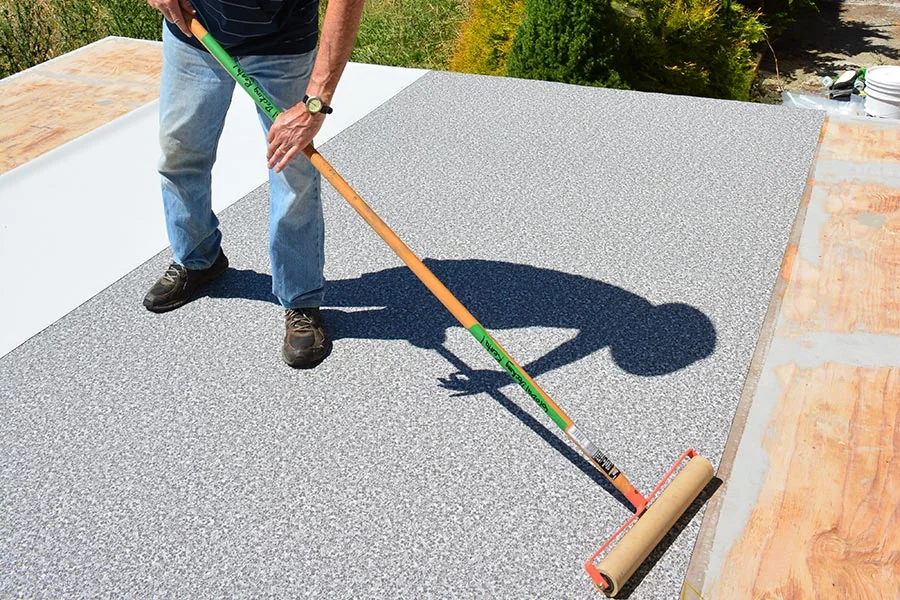 Installer rolling a patterned vinyl deck membrane onto a prepared plywood substrate